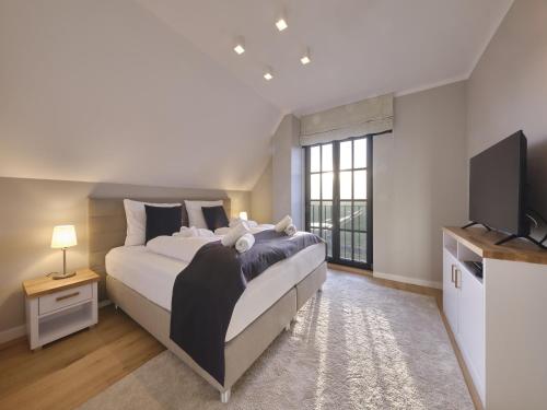 a bedroom with a large bed and a flat screen tv at Reetland am Meer - LuxusPlus Reetdachvilla mit 4 Schlafzimmern, Außensauna, Loungebereich und Kamin G07 in Dranske