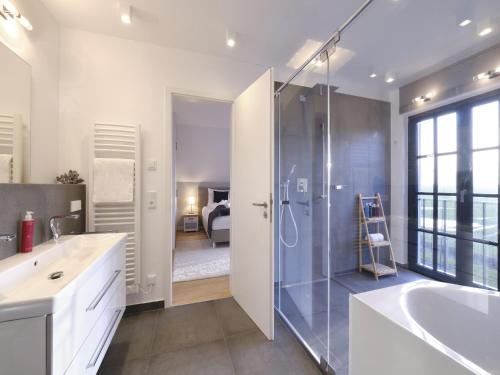 a bathroom with a shower and a sink and a tub at Reetland am Meer - LuxusPlus Reetdachvilla mit 4 Schlafzimmern, Außensauna, Loungebereich und Kamin G07 in Dranske