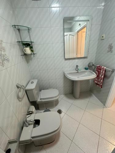 a white bathroom with a toilet and a sink at apartamento da marginal in Esposende