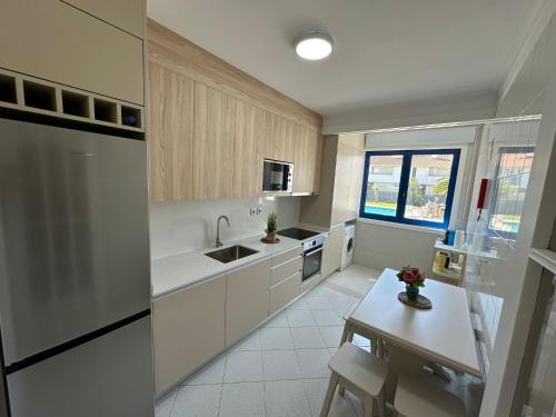 a kitchen with white appliances and a table in it at apartamento da marginal in Esposende