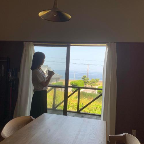 a woman standing in a room looking out a window at ワタリグラスハウス in Gamō