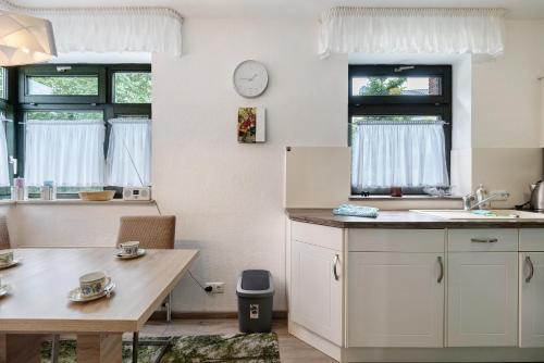 a kitchen with white cabinets and a table and windows at Fewo Strandmuschel in Dangast