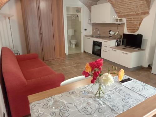 a living room with a red couch and a table with flowers at Ca' D'Rosina in Narzole
