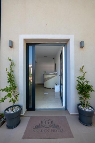 a door to a building with two potted plants at Golden Hotel in Ksamil