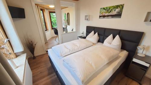 a bed with white pillows on it in a room at Hotel Schneiderhof in Braunlage
