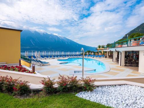 a resort with a swimming pool with mountains in the background at Hotel Cristina in Limone sul Garda