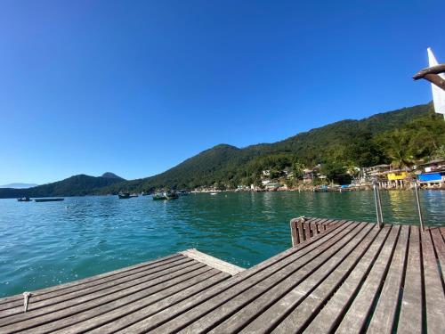 a dock on a lake with mountains in the background at Pousada Convés - Ilha Grande in Praia de Araçatiba