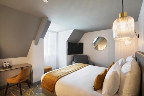 Habitación de hotel con cama, escritorio y espejo. en Hôtel & Spa Le Maury, Vannes, The Originals Boutique en Vannes