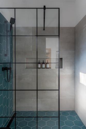 a shower with a glass door in a bathroom at BLACKWOOD Vendégház in Kesztölc