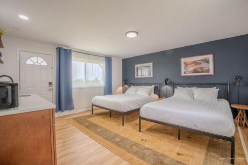 two beds in a room with blue walls and a kitchen at The Inn at Shady Pines in Gros Cap