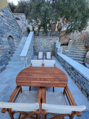a wooden table with white chairs and a stone wall at Casa Nostra Maisonette in Oítilon
