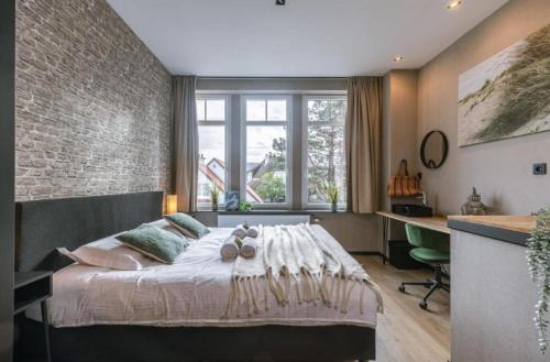 een slaapkamer met een bed en een bakstenen muur bij loftlivinq@sea in Middelkerke