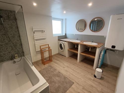 a bathroom with a tub and a sink and a washing machine at La C-onciergerie in Camblain-lʼAbbé