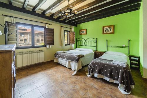 Dos camas en una habitación con paredes verdes. en La Pedraja de Atapuerca, en Galarde