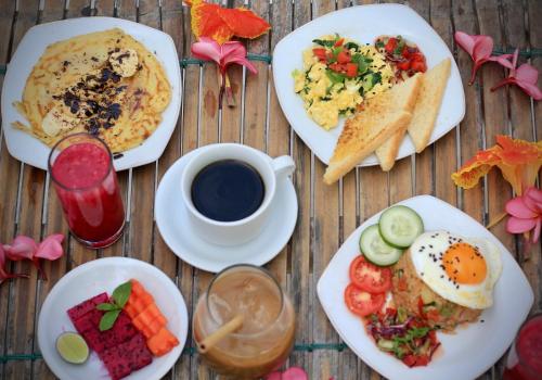 a table with plates of breakfast food and a cup of coffee at Kaktus bungalow 3 in Gili Air