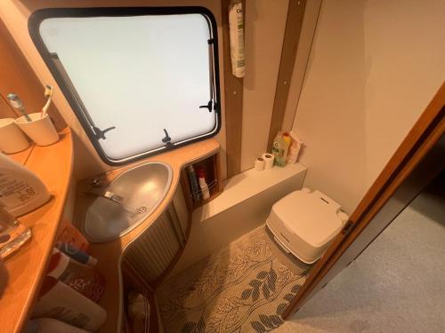 a small bathroom with a toilet and a sink at Dębki przyczepa kempingowa Fendt in Dębki