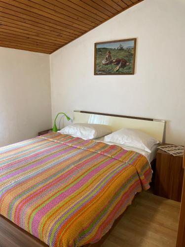 a bedroom with a bed with a colorful striped comforter at Apartments VUK in Jagodje