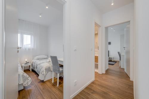 a white bedroom with a bed and a table at Centrally located apartments, free parking in Trogir