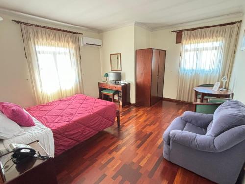 um quarto com uma cama, um sofá e uma cadeira em Hotel Trindade Coelho em Mogadouro