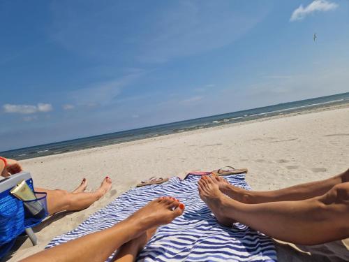 two people sitting on a towel on the beach at App 8u Heimatliebe in Dranske