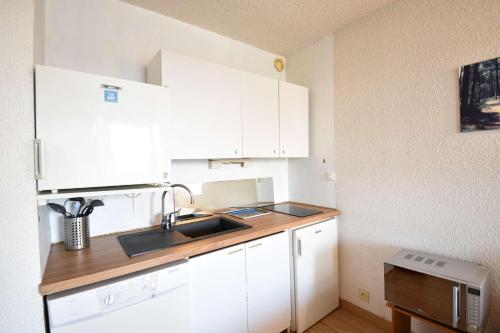 une cuisine avec des armoires blanches et un évier dans l'établissement Résidence Les Terrasses de Notre Dame, bel appartement avec vue sur l'entrée du port, à Capbreton