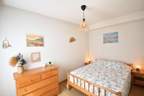 une chambre avec un lit et une commode en bois dans l'établissement Résidence Les Terrasses de Notre Dame, bel appartement avec vue sur l'entrée du port, à Capbreton