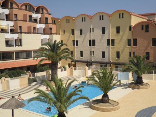 - une vue sur un complexe avec des palmiers et des bâtiments dans l'établissement Appt 2 pièces cabine avec piscine et parking à Gruissan - FR-1-229-773, à Gruissan