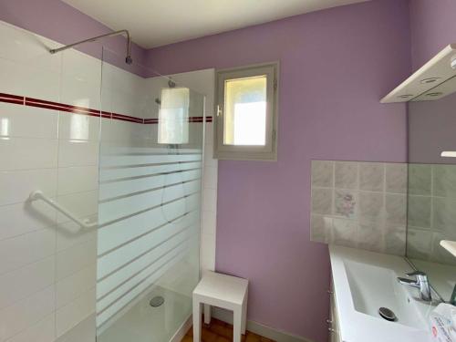 La salle de bains est pourvue de murs violets, d'un lavabo et d'une douche. dans l'établissement Maison 2** avec Jardin, Terrasse et Parking Privé à 800m de la Plage de Trestraou, Perros-Guirec - FR-1-542-23, à Perros-Guirec