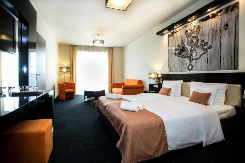 a hotel room with a large bed and a chair at Gotthard Therme Hotel & Conference in Szentgotthárd