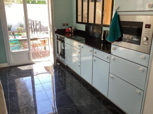 Il comprend une cuisine avec des placards blancs et du carrelage noir au sol. dans l'établissement Sous le garlaban, à Aubagne