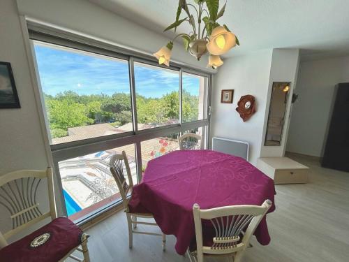 une salle à manger avec une table violette et une grande fenêtre dans l'établissement Appartement T2 avec Piscine et Garage au Centre-Plage d'Argelès-sur-Mer - FR-1-388-212, à Argelès-sur-Mer