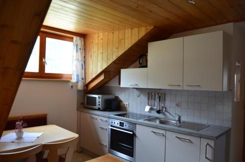 a kitchen with white cabinets and a sink and a table at Rauterhof in Hermagor