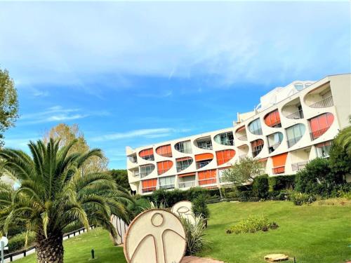 un bâtiment avec un palmier devant dans l'établissement Studio Rez-de-Jardin Proche Plage avec Parking - La Grande Motte - FR-1-790-27, à La Grande Motte