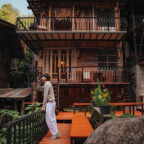 a man standing on a balcony of a house at ไชยพล โฮมสเตย์ หมู่บ้านแม่กำปอง in Ban Pok Nai