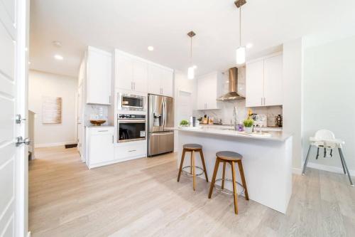 a kitchen with white cabinets and two bar stools at Beautiful Elegant Home Sleeps 10, Free Parking, Central AC in Edmonton