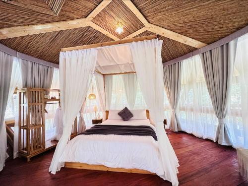 a bedroom with a canopy bed with white curtains at Alina Farm Resort- Two Bedroom Villa in Manolo Fortich