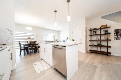 a kitchen with white cabinets and a dining room at Beautiful Elegant Home Sleeps 10, Free Parking, Central AC in Edmonton