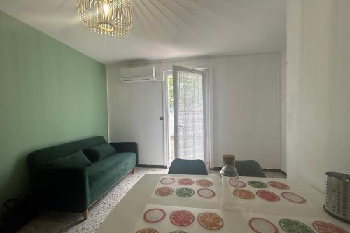 - un salon avec une table et un canapé vert dans l'établissement 2 air-conditioned rooms in villa by the sea, à Frontignan