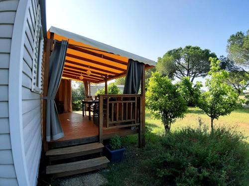 a wooden deck with a table on the side of a house at Mobil Home dans camping Lattes in Lattes
