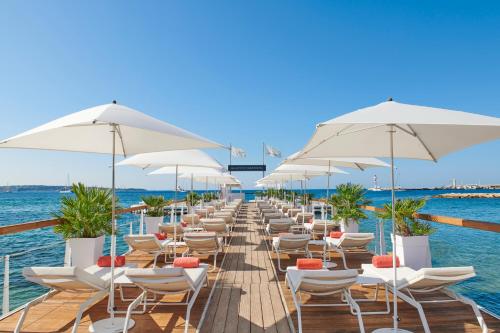 une rangée de chaises et de parasols sur un quai dans l'établissement Hôtel Barrière Le Majestic Cannes, à Cannes