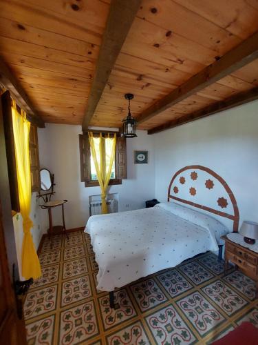 1 dormitorio con 1 cama grande y techo de madera en Las Peonías Casa Rural en Almiruete