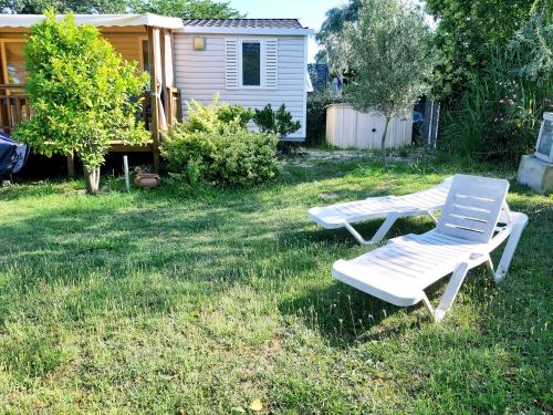 two lounge chairs sitting in the grass in a yard at Mobil Home dans camping Lattes in Lattes