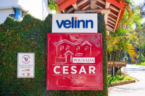 a red sign in front of a building at VELINN Pousada Cesar in Santo Antônio do Pinhal