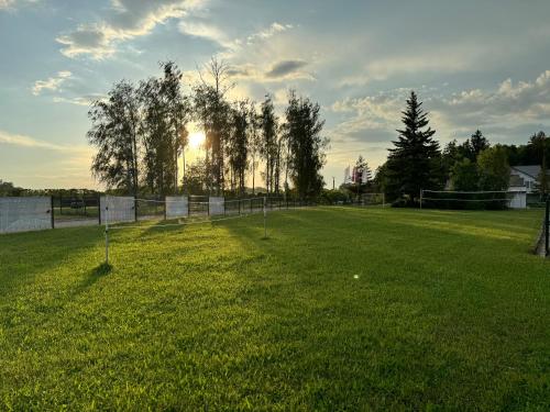 a field of grass with the sun in the background at Mūsa Kemping in Bauska