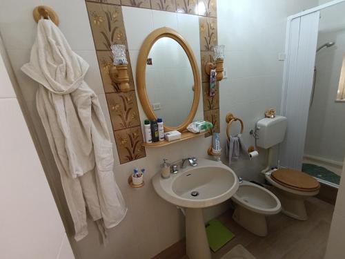 a bathroom with a sink and a toilet and a mirror at Casa del Saraceno in Ravanusa