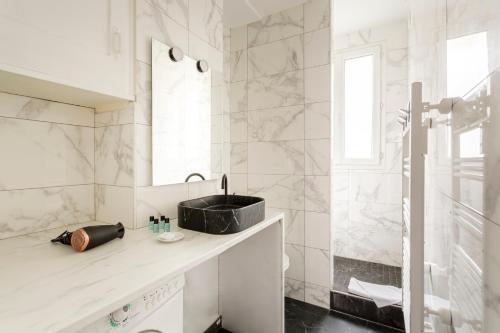 une salle de bain blanche avec un lavabo et une douche dans l'établissement Saint Paul le Marais Charlemagne, à Paris