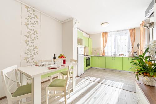 a kitchen with green cabinets and a white table and chairs at ARI - ARED Luxurious Apartments with Balcony & Free Parking in Arad