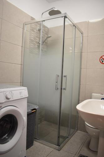 a glass shower in a bathroom with a washing machine at Mavrikios Luxury Apartment in Nea Kallikrateia