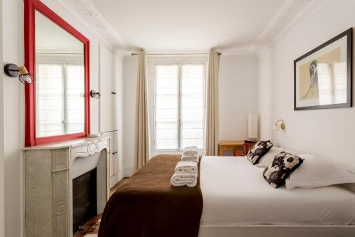 une chambre blanche avec un lit et une cheminée dans l'établissement Saint Paul le Marais Charlemagne, à Paris