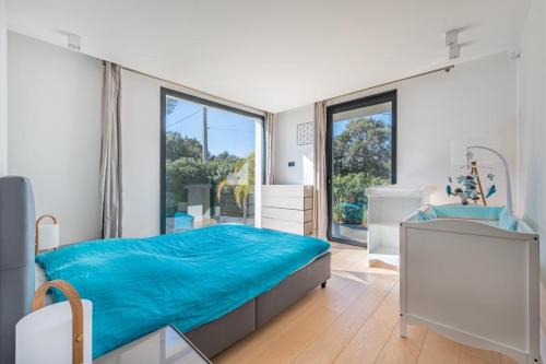 - une chambre avec un grand lit bleu et une fenêtre dans l'établissement villa La Pinède, à Cagnes-sur-Mer